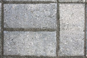Closeup of three paver bricks in a paved stone patio floor.